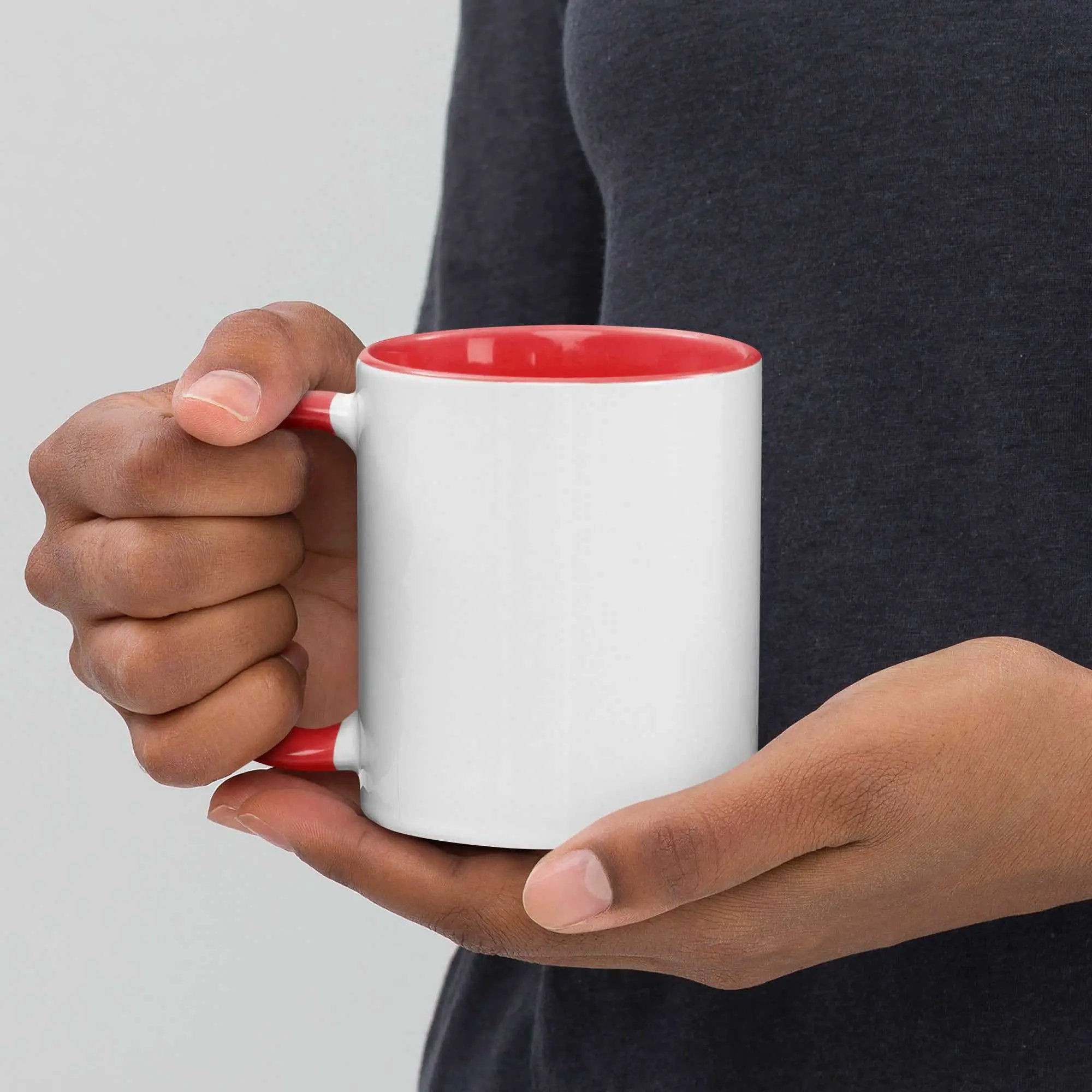 Person holding a white Caring for the Caregiver ceramic mug with a red interior and handle