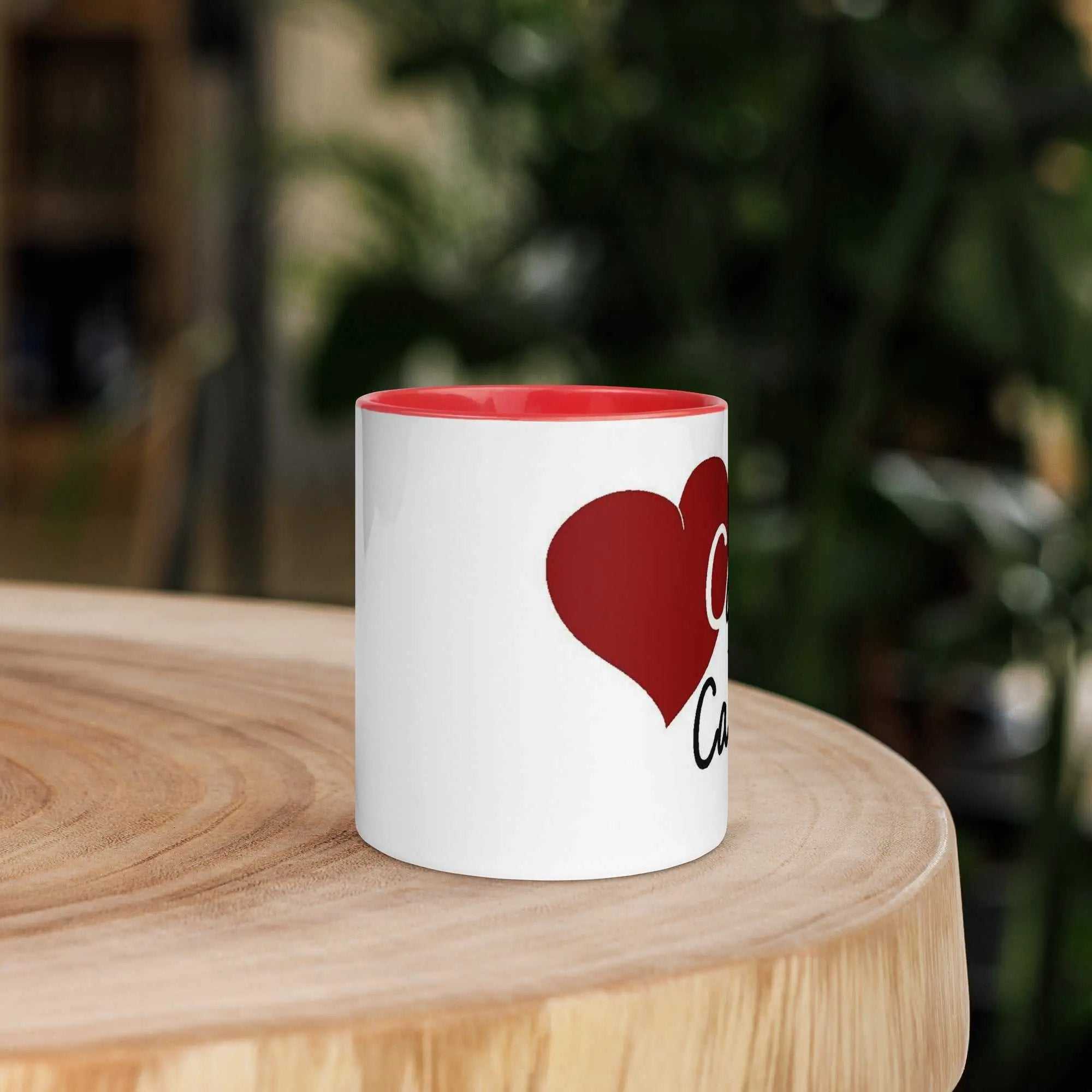 Caring for the Caregiver ceramic mug with red interior and heart graphic on wooden table