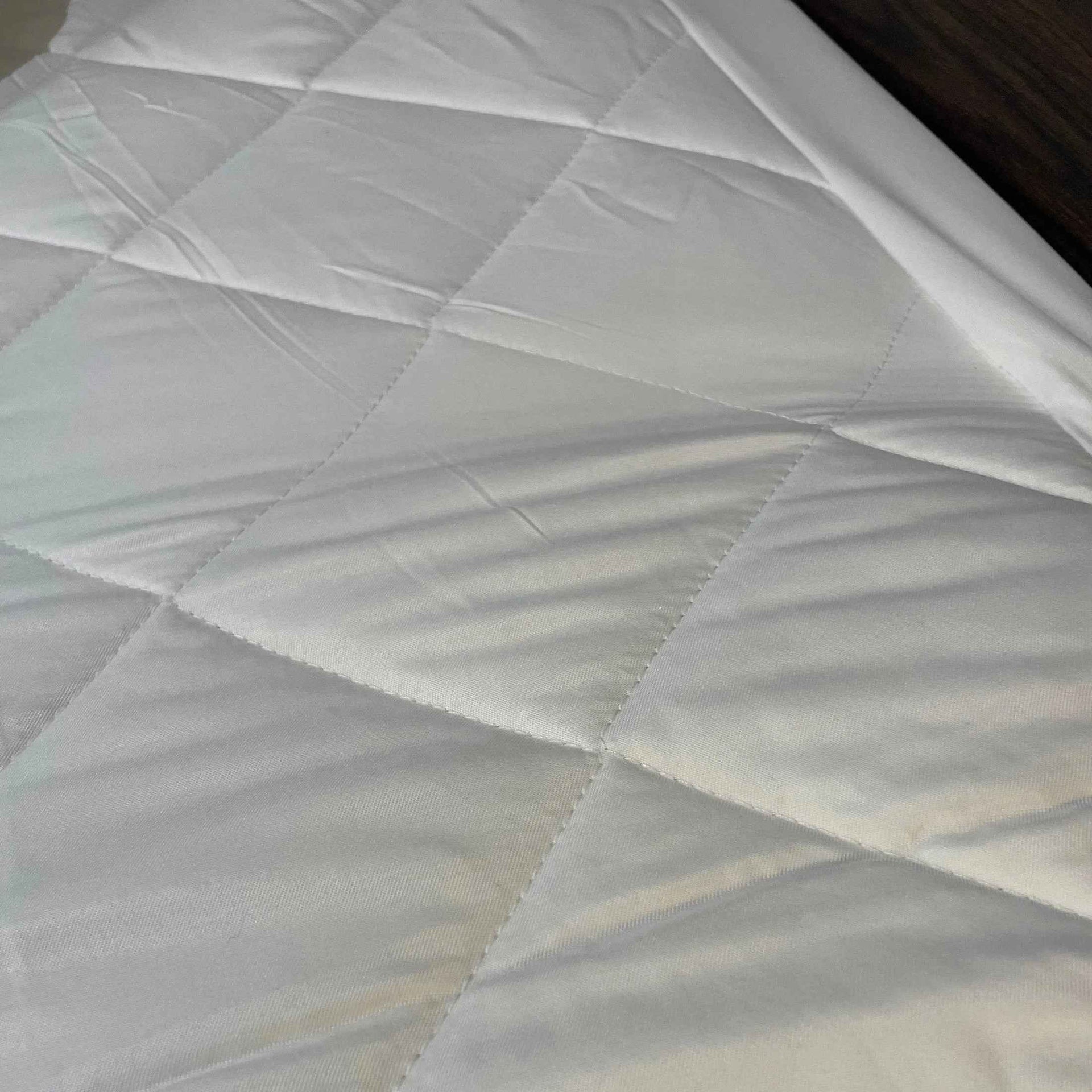 Quilted waterproof mattress protector from GOTL Collection by Rifz Textiles Inc, showcasing padded bedding accessory on a mattress.