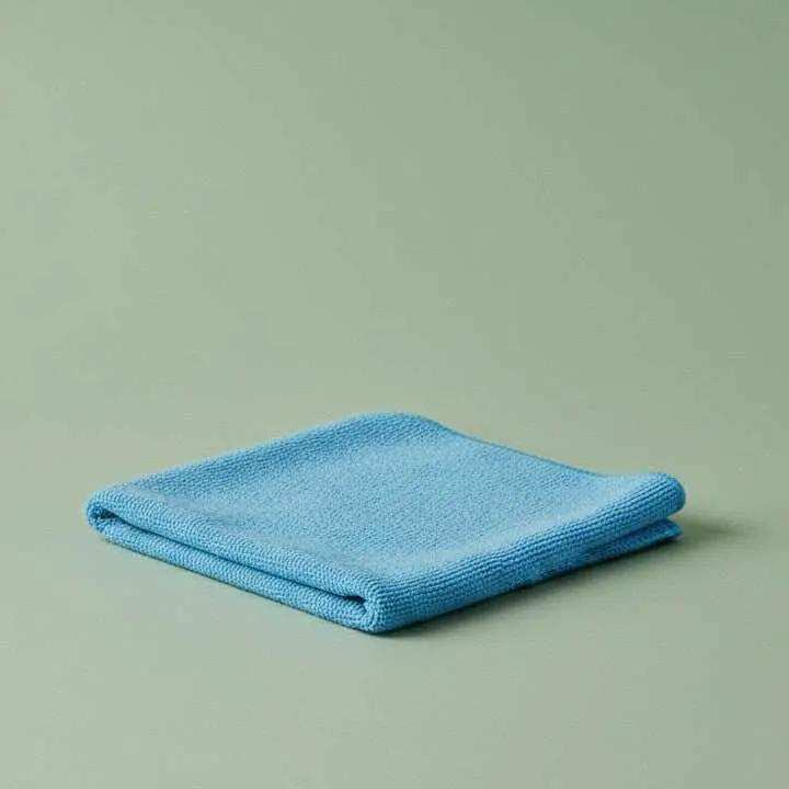 Blue microfiber cleaning cloth folded on a sage green background