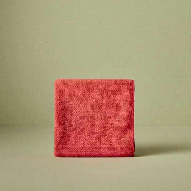 Folded red microfiber cleaning cloth on a light green background
