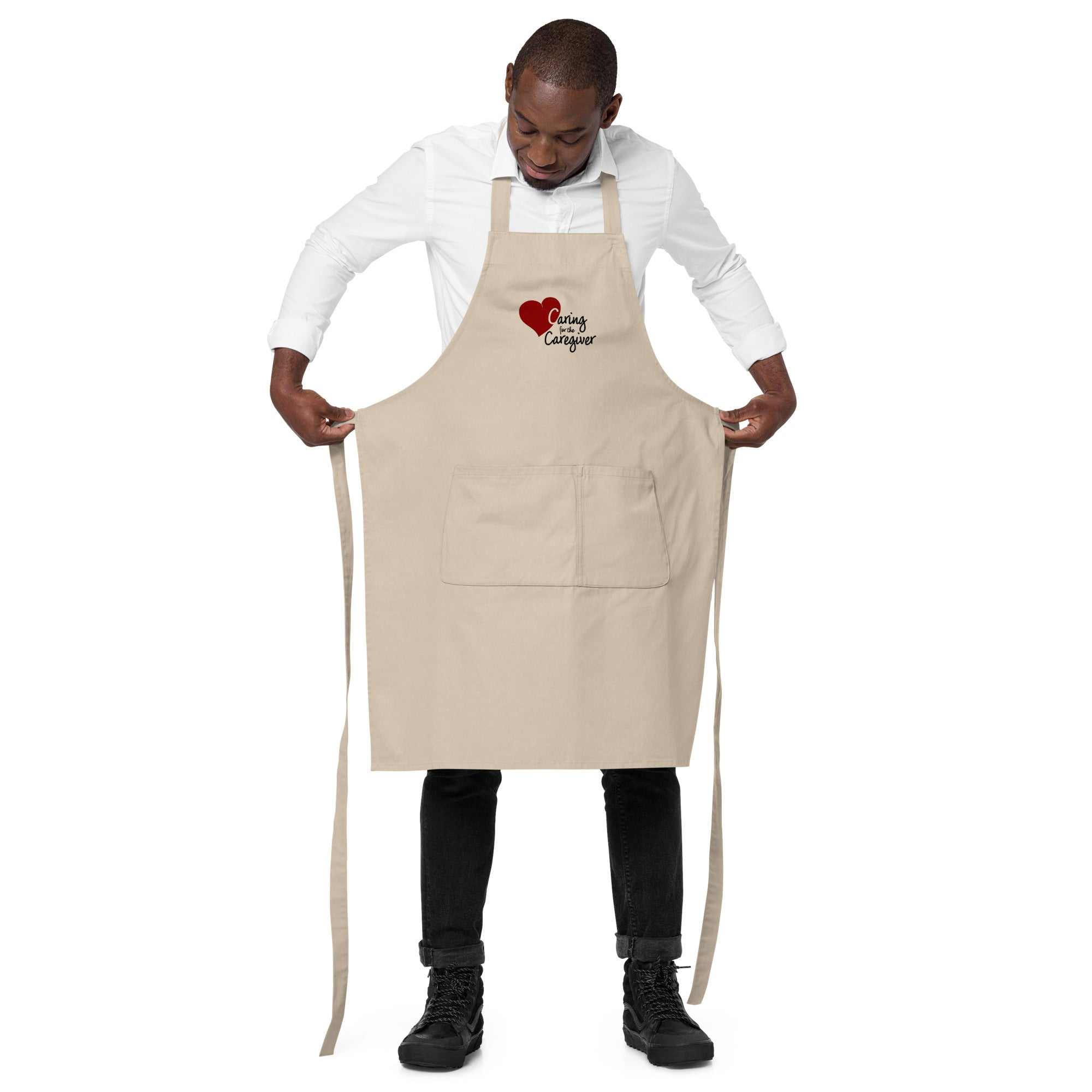 Man wearing a beige Caregiver Apron with a red heart graphic and text