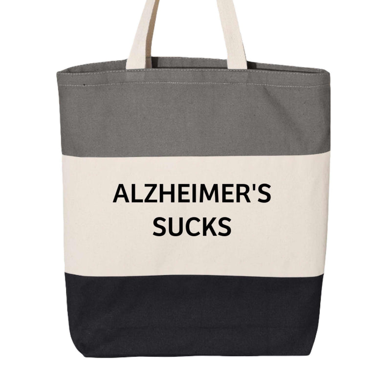 Tri-color tote bag with "Alzheimer's Sucks" print in black, natural, and light grey, stylish awareness accessory by Greg's AZ Store.