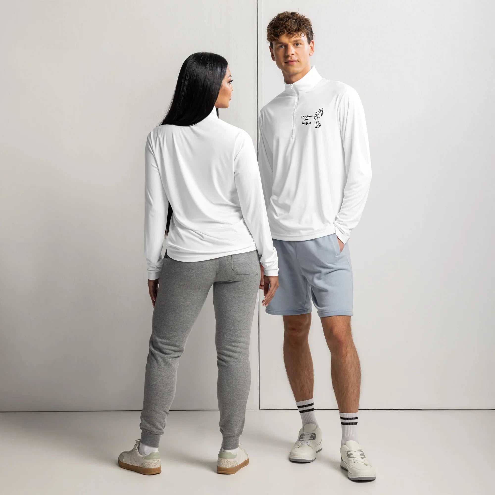 Man and woman wearing white lightweight quarter-zip pullovers with Caregivers Are Angels graphic