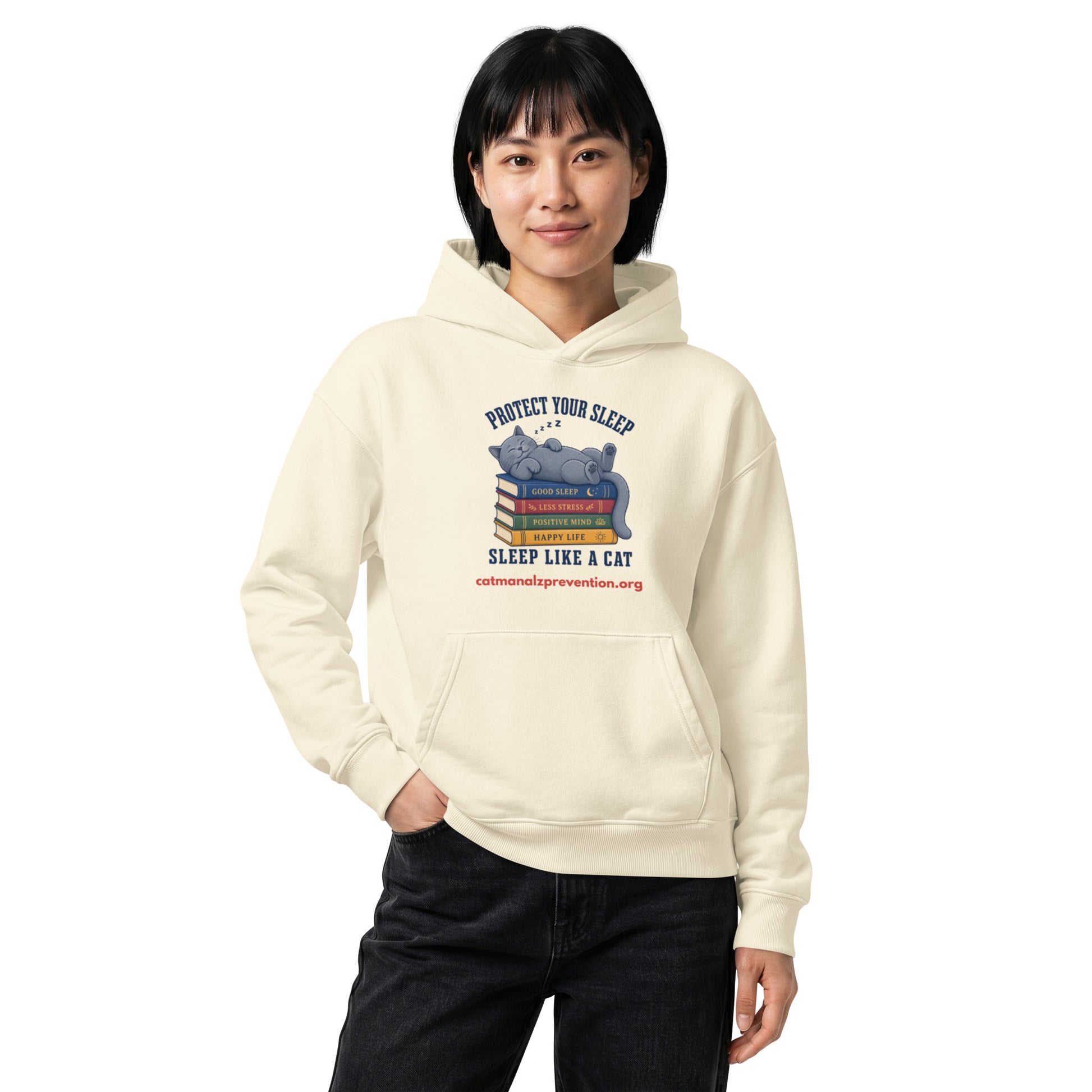 Person wearing a cream unisex relaxed mid-weight hooded sweatshirt with a cat sleeping on books graphic