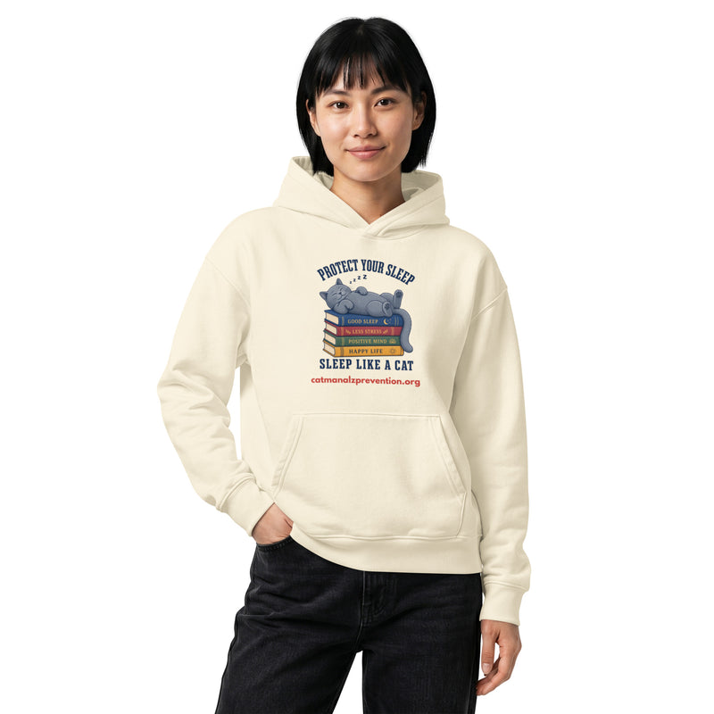 Person wearing a cream unisex relaxed mid-weight hooded sweatshirt with a cat sleeping on books graphic
