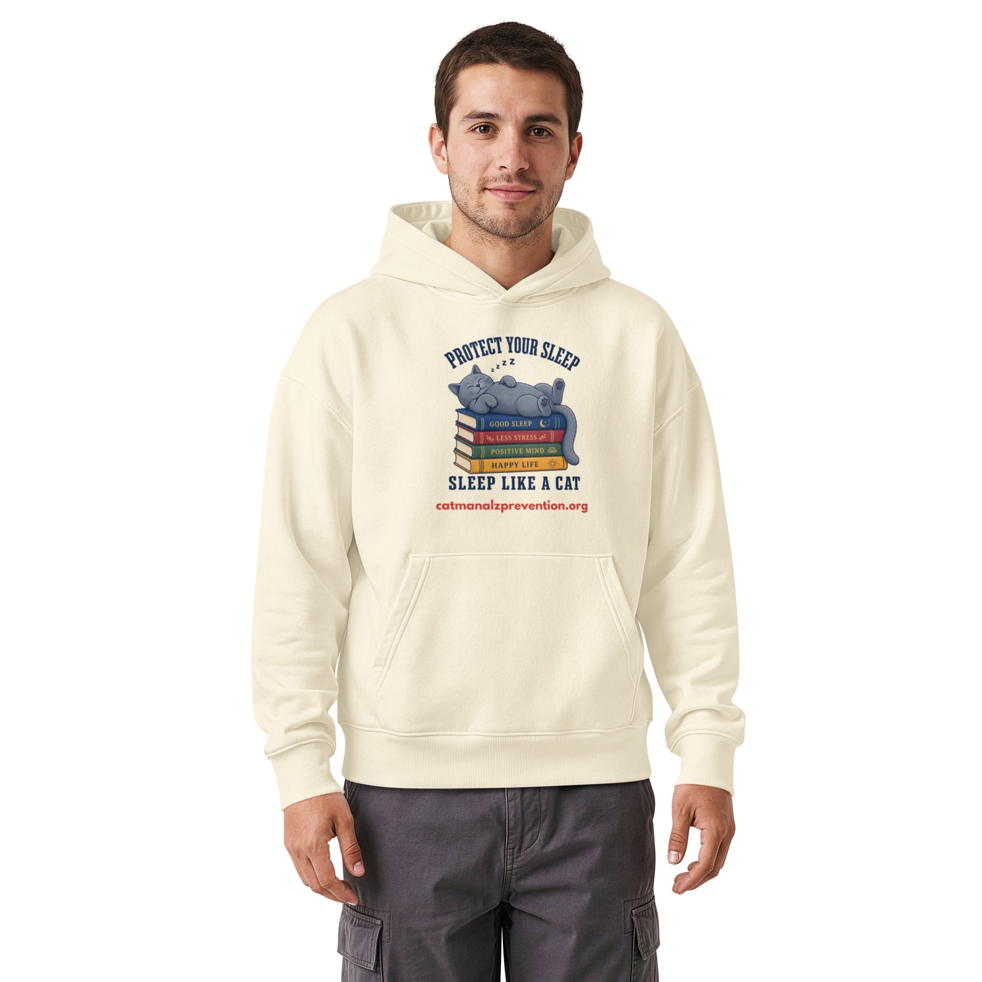 Man wearing a cream unisex relaxed mid-weight hooded sweatshirt with a cat sleeping on books graphic