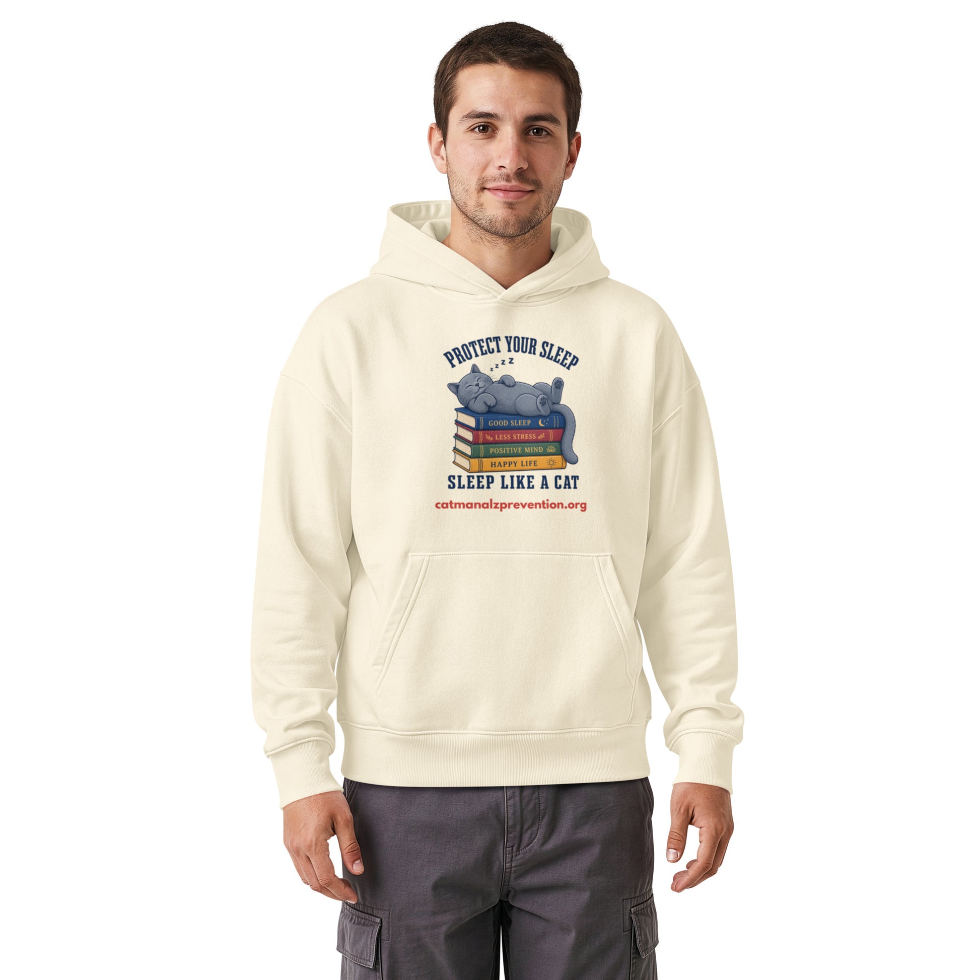 Man wearing a cream unisex relaxed mid-weight hooded sweatshirt with a cat sleeping on books graphic