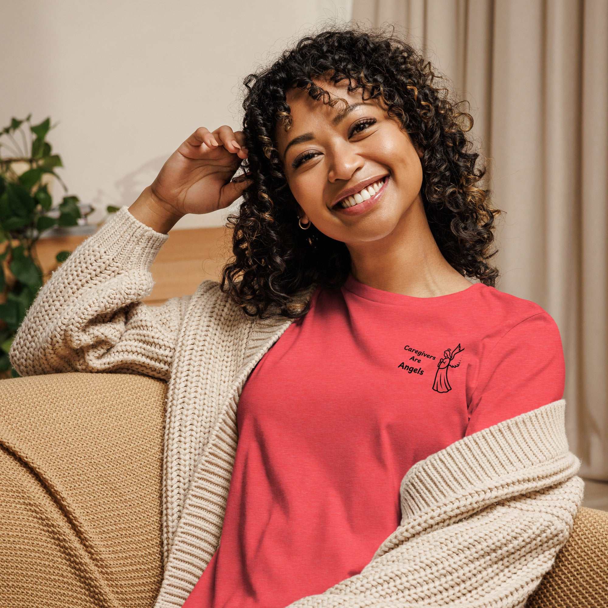 Woman wearing orange relaxed t-shirt with Caregivers Are Angels graphic and beige cardigan